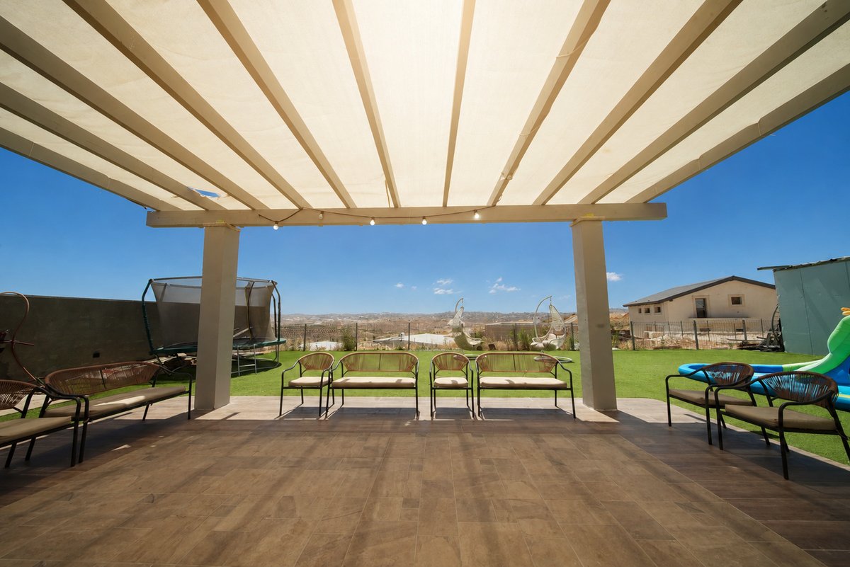 פרגולה מקורה עם פינות ישיבה ונוף להרי יהודה בחצר הוילה